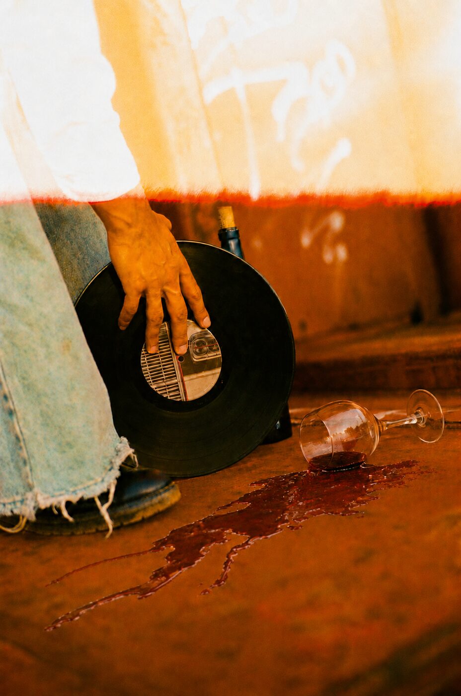 A hand on a record, red wine on rust-coloured ground